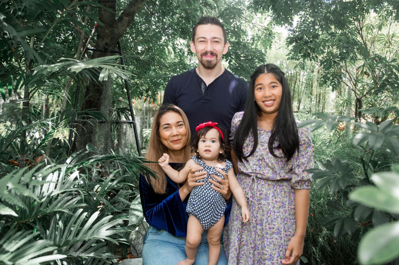 Family portrait of four smiling in a green backyard, enjoying togetherness.