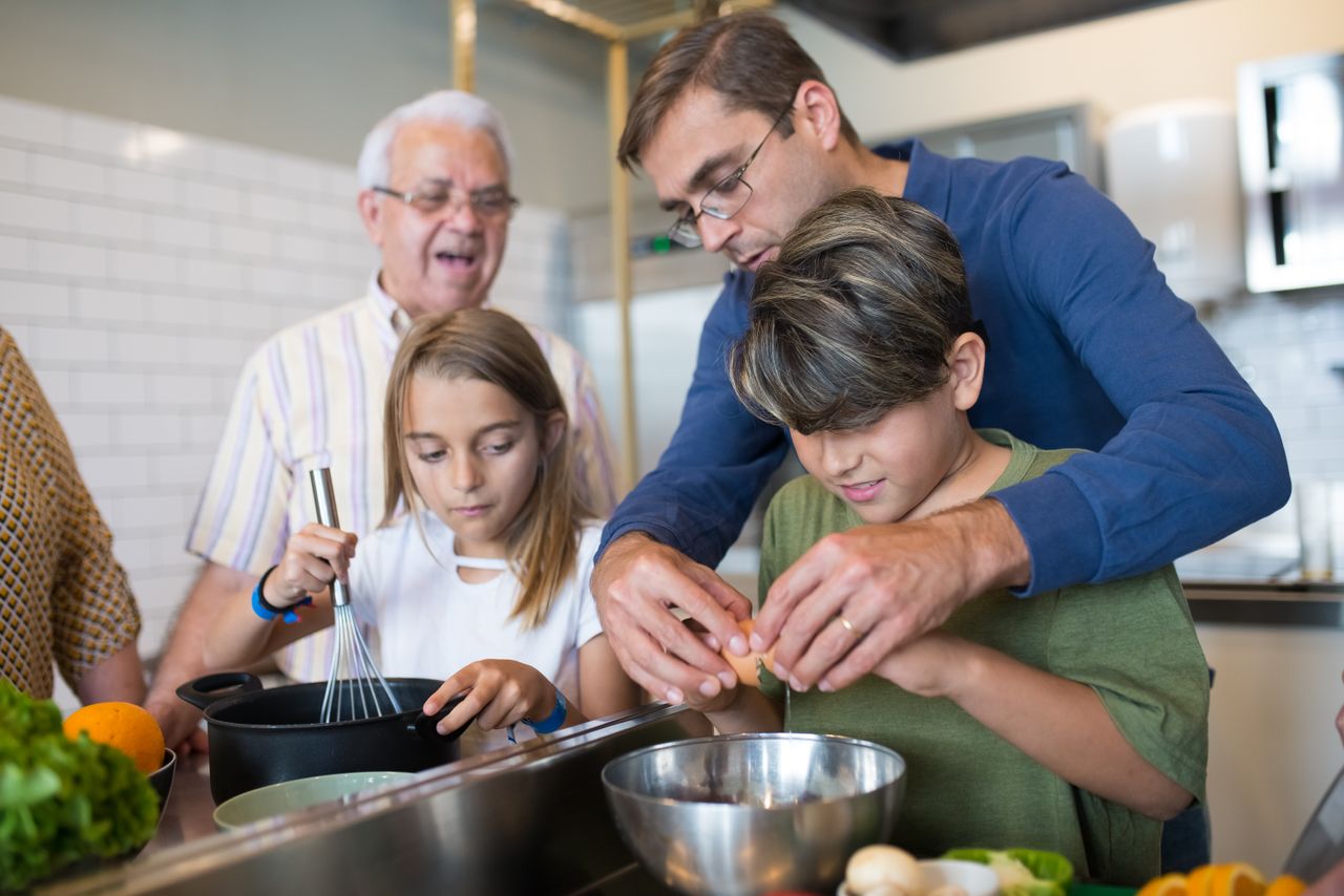 Three generations bond while preparing a meal, highlighting family and culinary traditions.