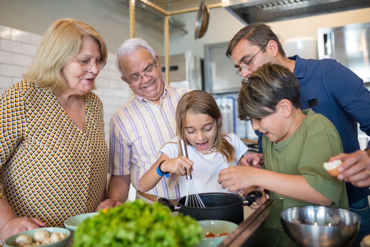 Happy family of five bonding and cooking together in a home kitchen.