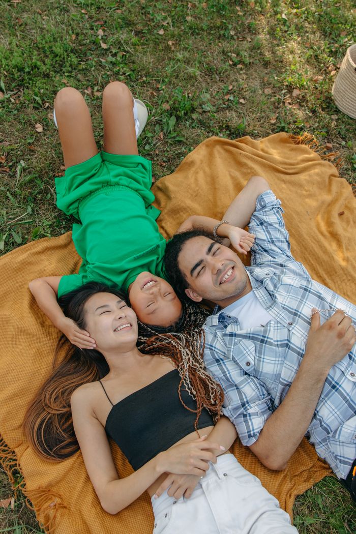 Happy multiracial family lying on a picnic blanket, enjoying a sunny day in the park.